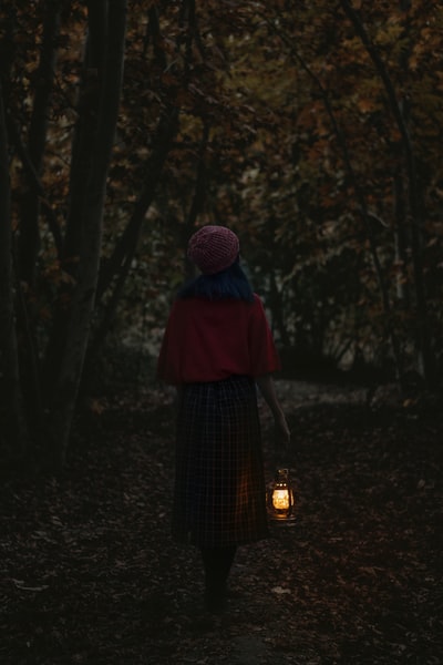 戴着紫色针织帽和黑色连衣裙的女人站在森林里